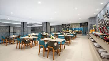 A modern dining area with multiple tables and chairs, a buffet line with various dishes, and a decorative wall with geometric patterns.