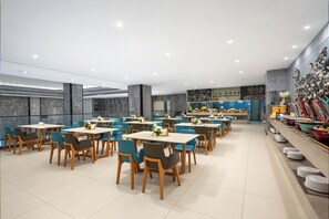 A modern dining area with multiple tables and chairs, a buffet line with various dishes, and a decorative wall with geometric patterns. - AMBER CRYSTALINTERNATIONAL HOTEL (Shenzhen)