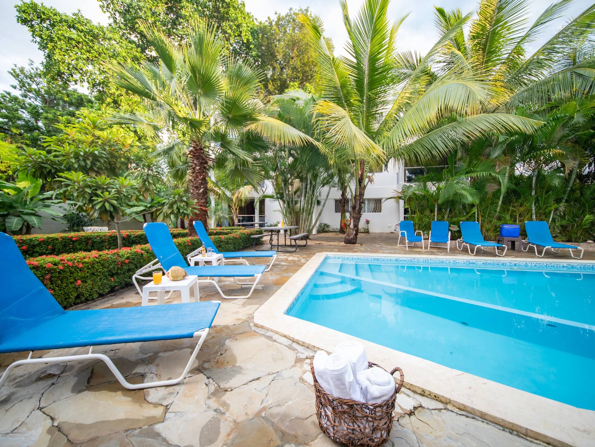 A swimming pool with blue lounge chairs and a wicker basket with towels.
