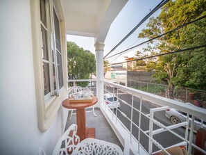 A balcony with a table and chairs, a view of the street, and a building with a green roof. - Studio in Sosua Center! Near Sosua beach (Sosúa)