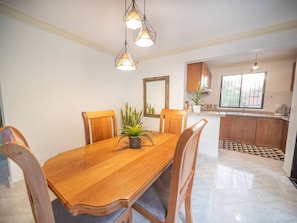 A dining area with a wooden table, chairs, and hanging pendant lights. - Affordable 2BR APT in Sosua Center! (Sosúa)