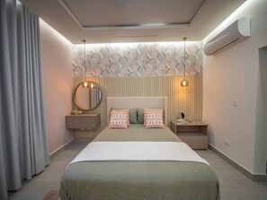 Un dormitorio moderno con cama, mesitas de noche, un espejo y aire acondicionado de pared.