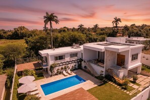 A modern two-story house with a swimming pool, surrounded by greenery and palm trees. - Stylish Luxury Villa in Sosua- 5BR Suites! (Sosúa)