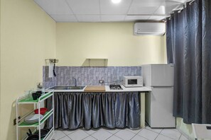 Eine kleine Küche mit Spüle, Mikrowelle, Herd und Kühlschrank.