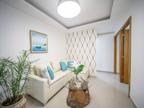 A modern living room with a sofa, a coffee table, and a potted plant. - Modern  2BR Apt Central in Sosua (Sosúa)