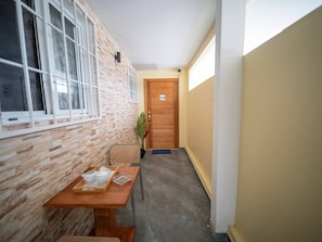 A hallway with a wooden door marked 'U4', a reception desk with a plant, and a window with blinds. - Modern  2BR Apt Central in Sosua (Sosúa)