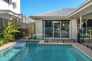 A modern pool area with clear water, surrounded by a glass fence, and adjacent to a building with large windows. - Saltwater Haven - Pool, Beach & Dog-Friendly (Mooloolaba Region)