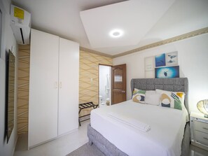 A bedroom with a bed, a wardrobe, a bathroom, and a wall with ocean-themed artwork. - Room in the center with Outdoor Jacuzzi (Sosúa)