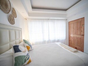 A bedroom with a large bed, a wooden wardrobe, and a window with sheer curtains. - Room in Sosua center with Outdoor Jacuzzi (Sosúa)