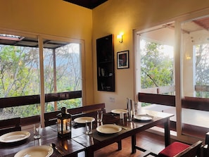 A dining area with a table set for two, a lantern, and a bookshelf. - Auranya The Himalayan Jungle Retreat (Choubattakhal)