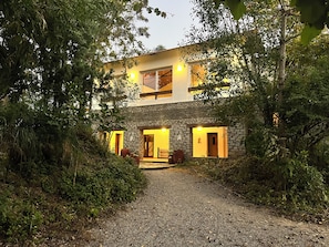 A two-story building with a stone facade, multiple windows, and a gravel driveway leading to the entrance. - Auranya The Himalayan Jungle Retreat (Choubattakhal)