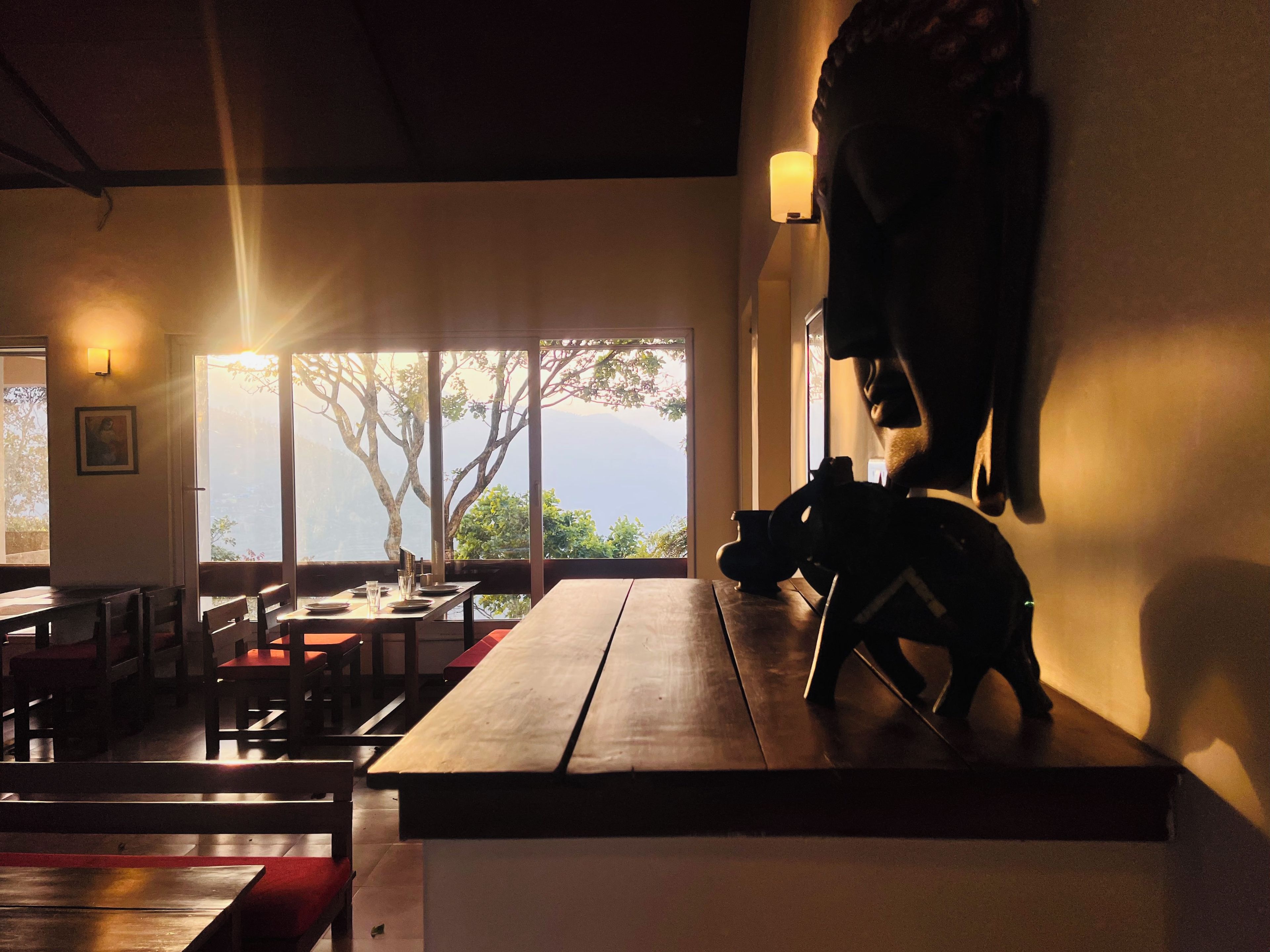 Un interior con comedor, un ventanal con vistas y una estatua sobre una mesa.
