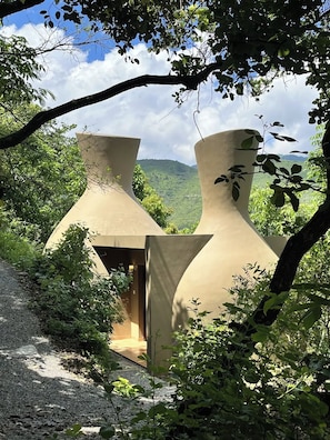 Una casa de l'arbre moderna i minimalista, amb un disseny únic i orgànic, envoltada de vegetació exuberant i una vista despejada del paisatge.