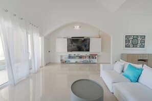 Ein modernes Wohnzimmer mit Fernseher, einer Couch, einem Couchtisch und einem Bücherregal.