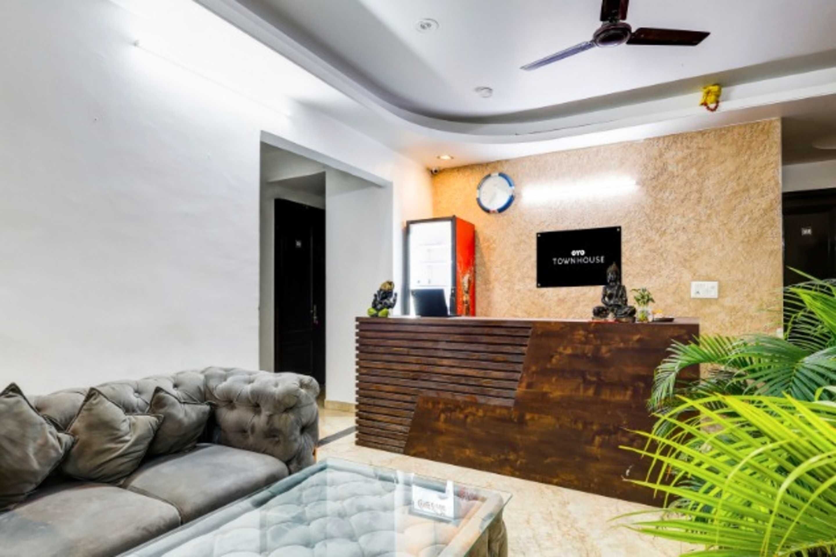 A reception area with a modern design, including a sofa, a reception desk, and a clock on the wall.