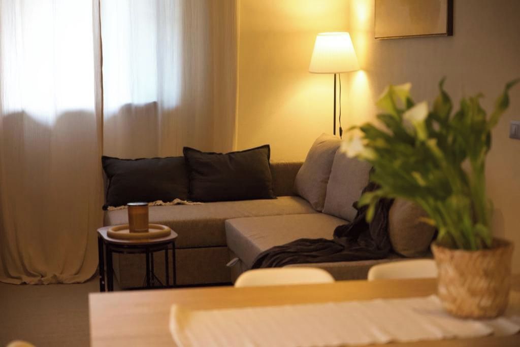Une chambre d’hôtel avec un canapé, une petite table d’appoint, une lampe et une plante en pot.