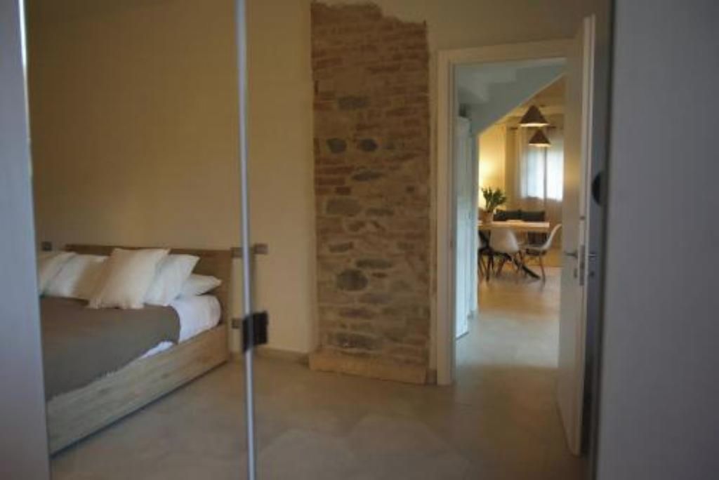 Una camera da letto con un letto, un muro in pietra e vista su un'area pranzo.