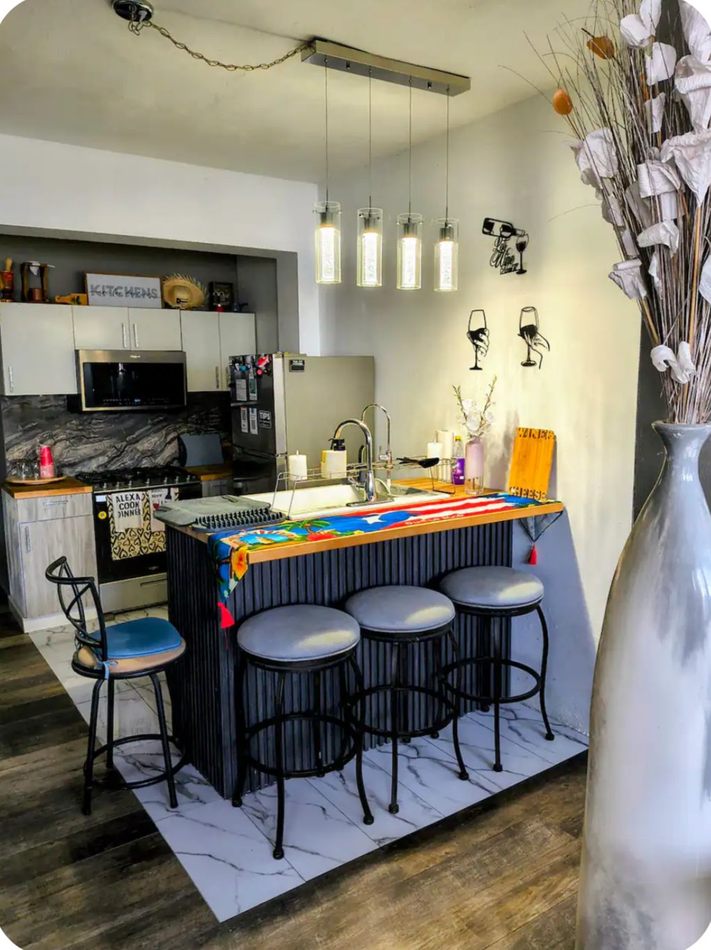A modern kitchen with a bar area, bar stools, and a decorative vase.