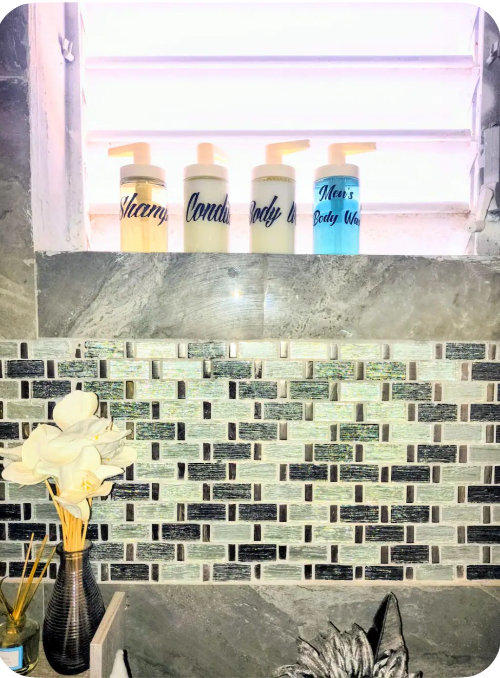 A bathroom with a tiled backsplash and a window above a vanity area.