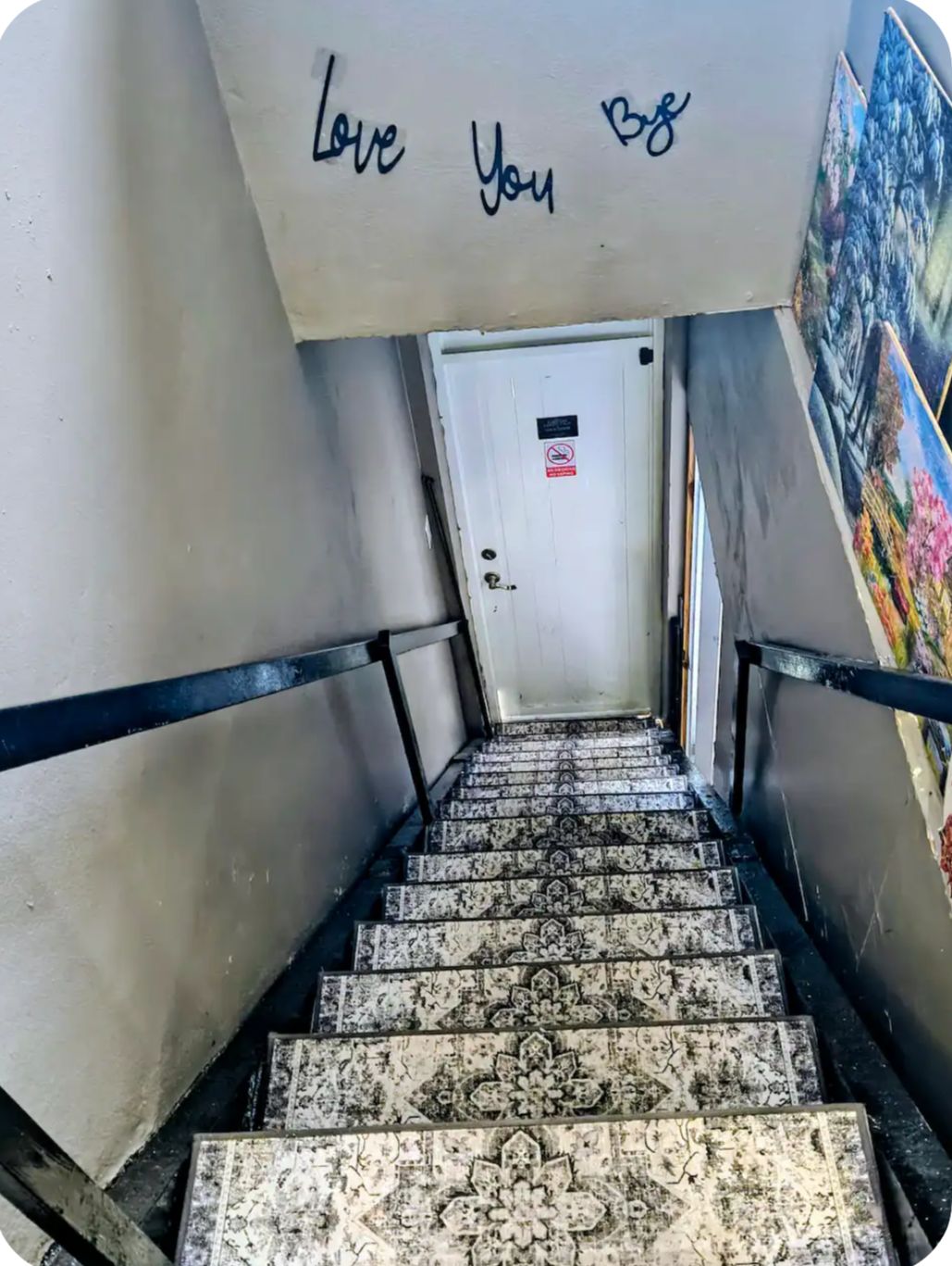 Uma escadaria com uma placa que diz 'Love You 98' acima de uma porta.
