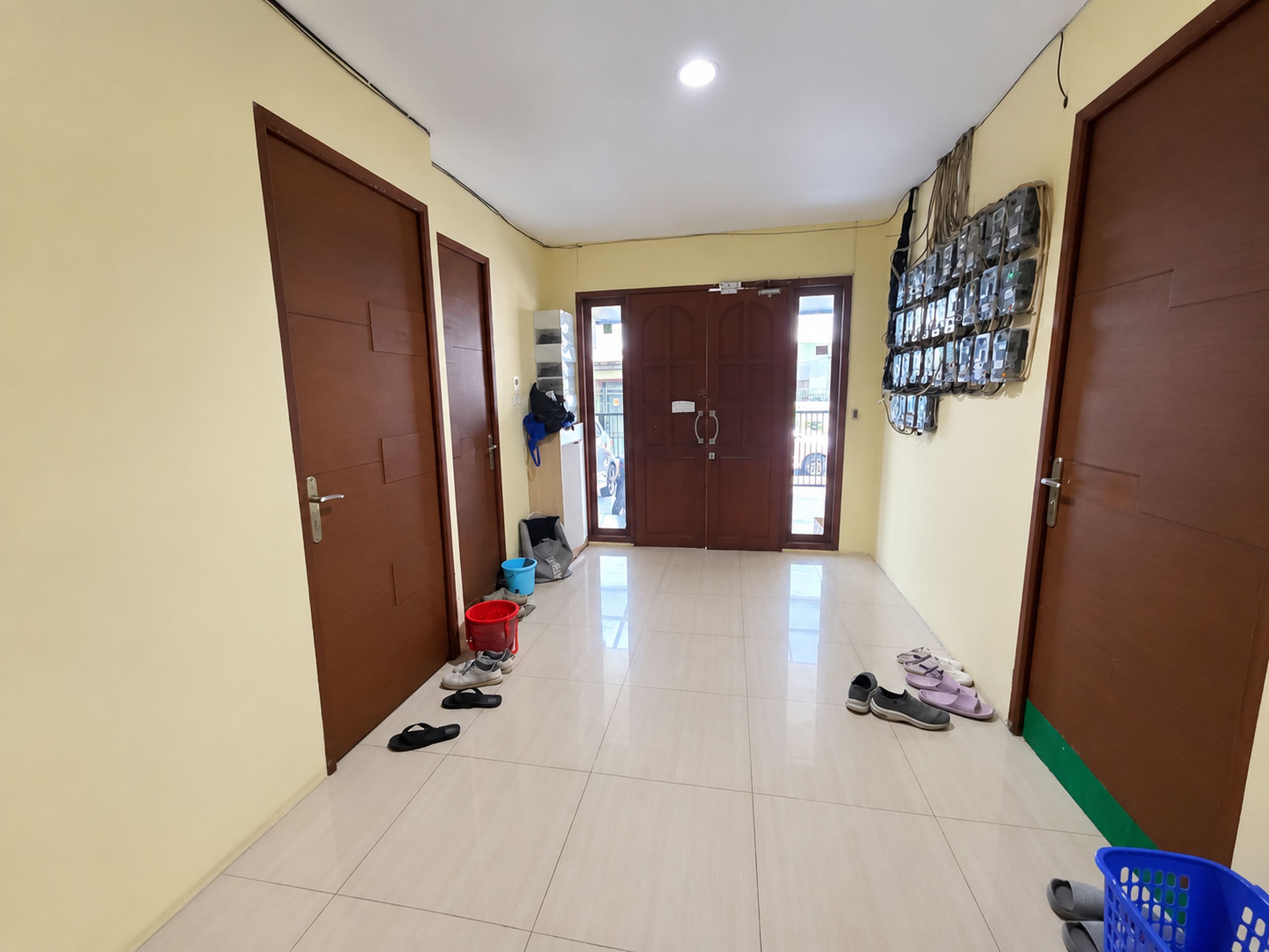 A hallway with two doors, a tiled floor, and a wall-mounted electrical panel.