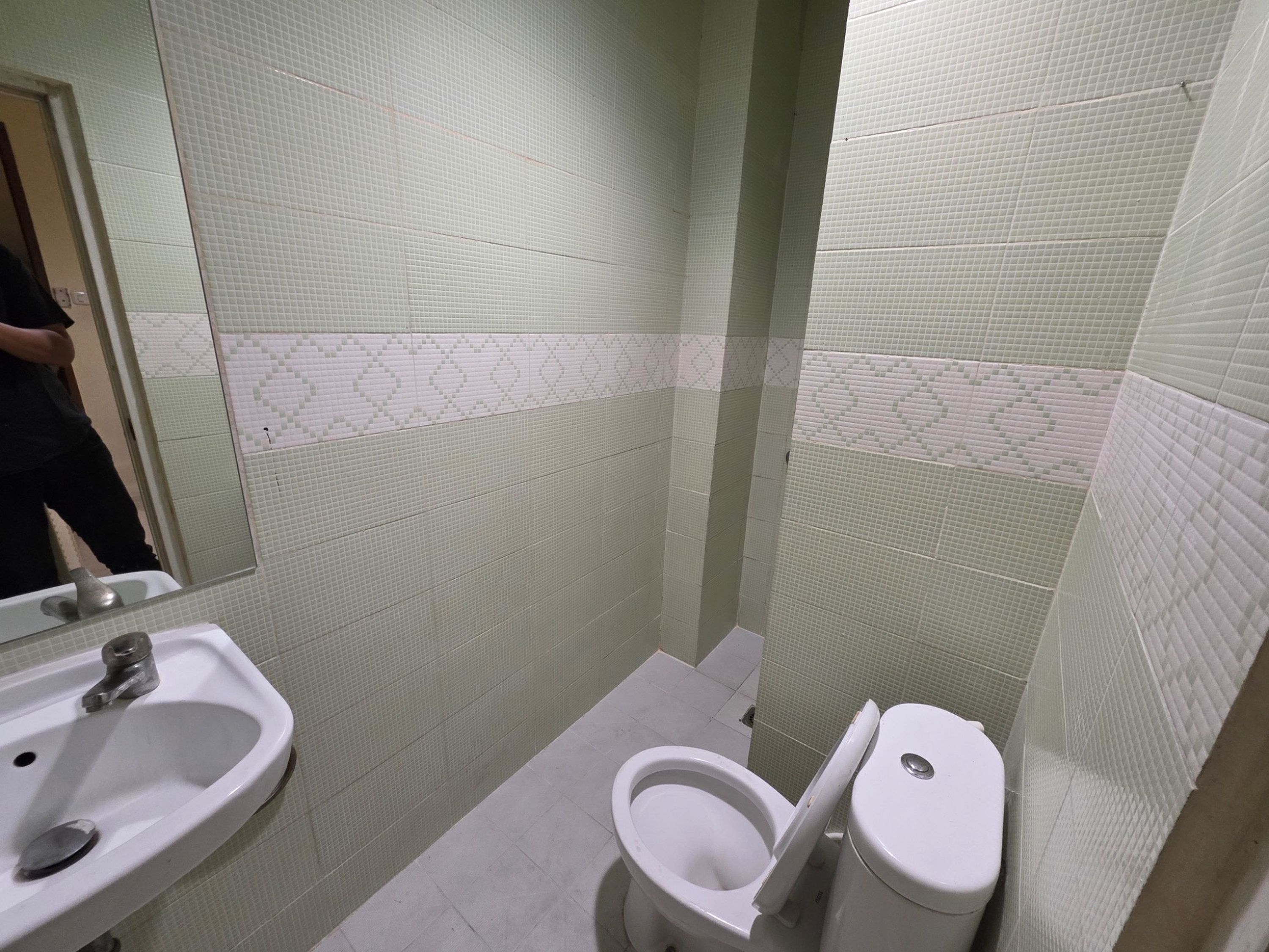 A bathroom with a sink, toilet, and tiled walls.