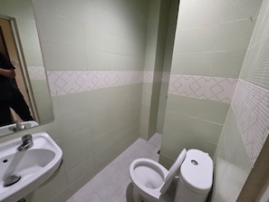 A bathroom with a sink, toilet, and tiled walls. - Hotel O near Mall Ciputra World  (Jakarta)