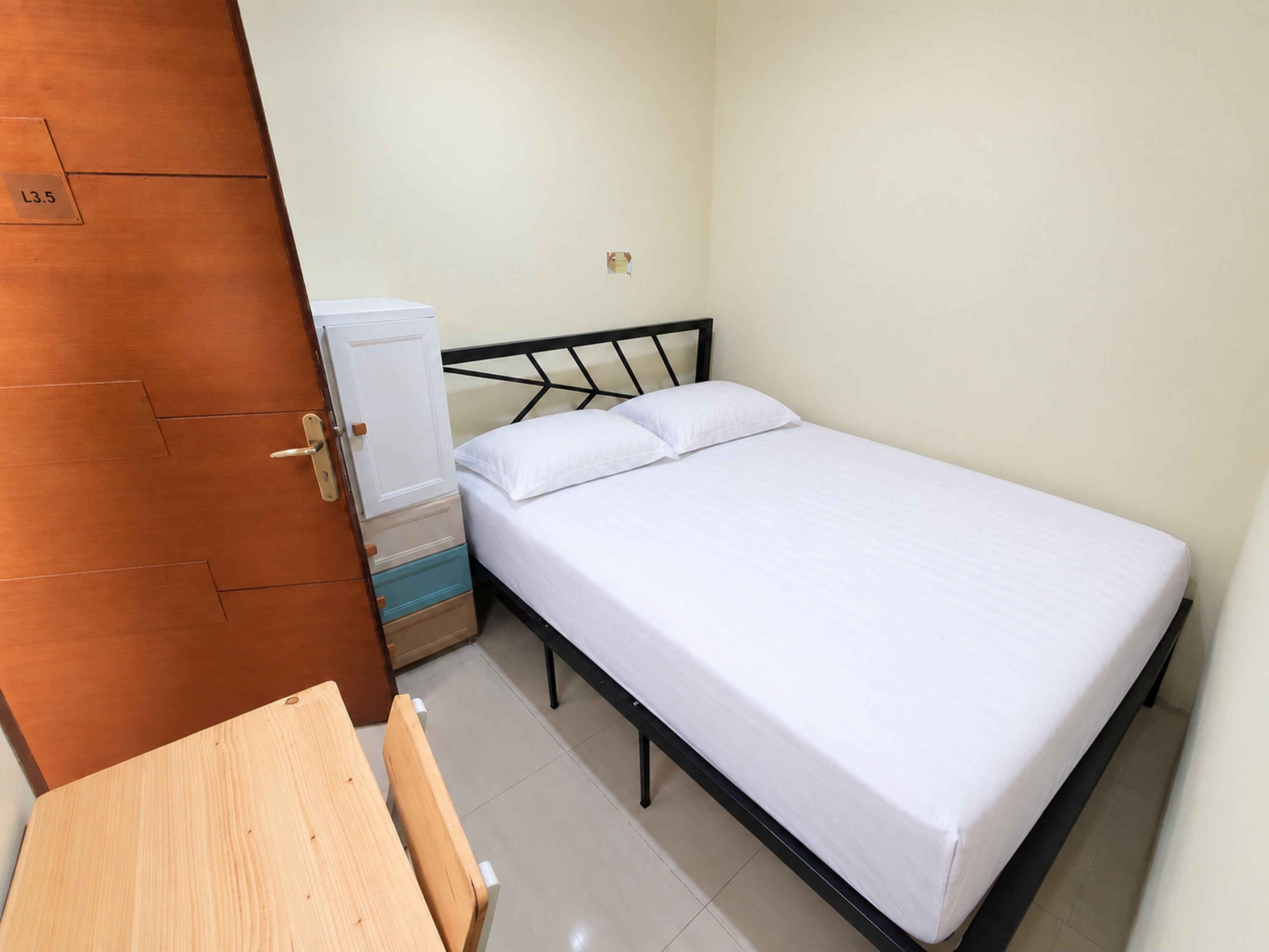 Een slaapkamer met een bed, een houten tafel en een kledingkast.