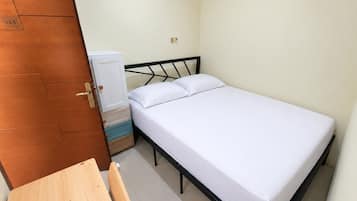 Een slaapkamer met een bed, een houten tafel en een kledingkast.