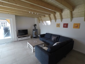 A living room with a sofa, a coffee table, a TV, and a fireplace. - Pure sea Breeze (Wurster Nordseeküste)