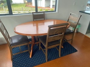 A dining area with a round table, four chairs, and a blue patterned rug. - Short Walk to Tokerau (Karikari Peninsula)