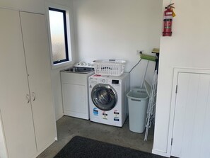 A laundry room with a washing machine, dryer, and a fire extinguisher. - Short Walk to Tokerau (Karikari Peninsula)