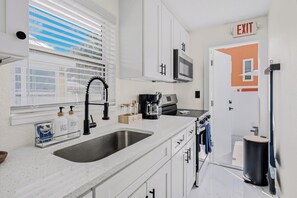 A modern kitchen with a double sink, a microwave, and a coffee machine. - Blue Lagoon at White Sands| 2br/1ba close to beach (Indian Rocks Beach)