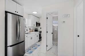 A modern kitchen with white cabinets, a stainless steel refrigerator, a microwave, and a stove. - White Sands Beach Cottages| 6 cottages sleeps 32 (Indian Rocks Beach)