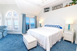 A bedroom with a large bed, two bedside tables, a nightstand, a window with curtains, a view of the sea, and a balcony. - OCEANFRONT-Ocean Views, ELEV, Priv Pool, Hot Tub-S16, Voulez-Vous (Corolla)