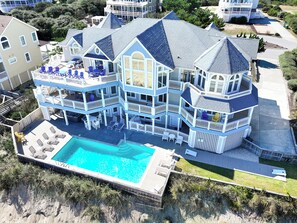 A multi-story beachfront property with a swimming pool, multiple balconies, and outdoor seating areas. - OCEANFRONT-Ocean Views, ELEV, Priv Pool, Hot Tub-S16, Voulez-Vous (Corolla)