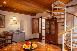 A kitchen with a dining table, a fruit bowl, a wooden staircase, and a cabinet. - Casa Masaccio by Maison Florence (Florence)