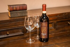 A bottle of wine with a label, two empty wine glasses, and two books on a wooden surface. - Casa Masaccio by Maison Florence (Florence)