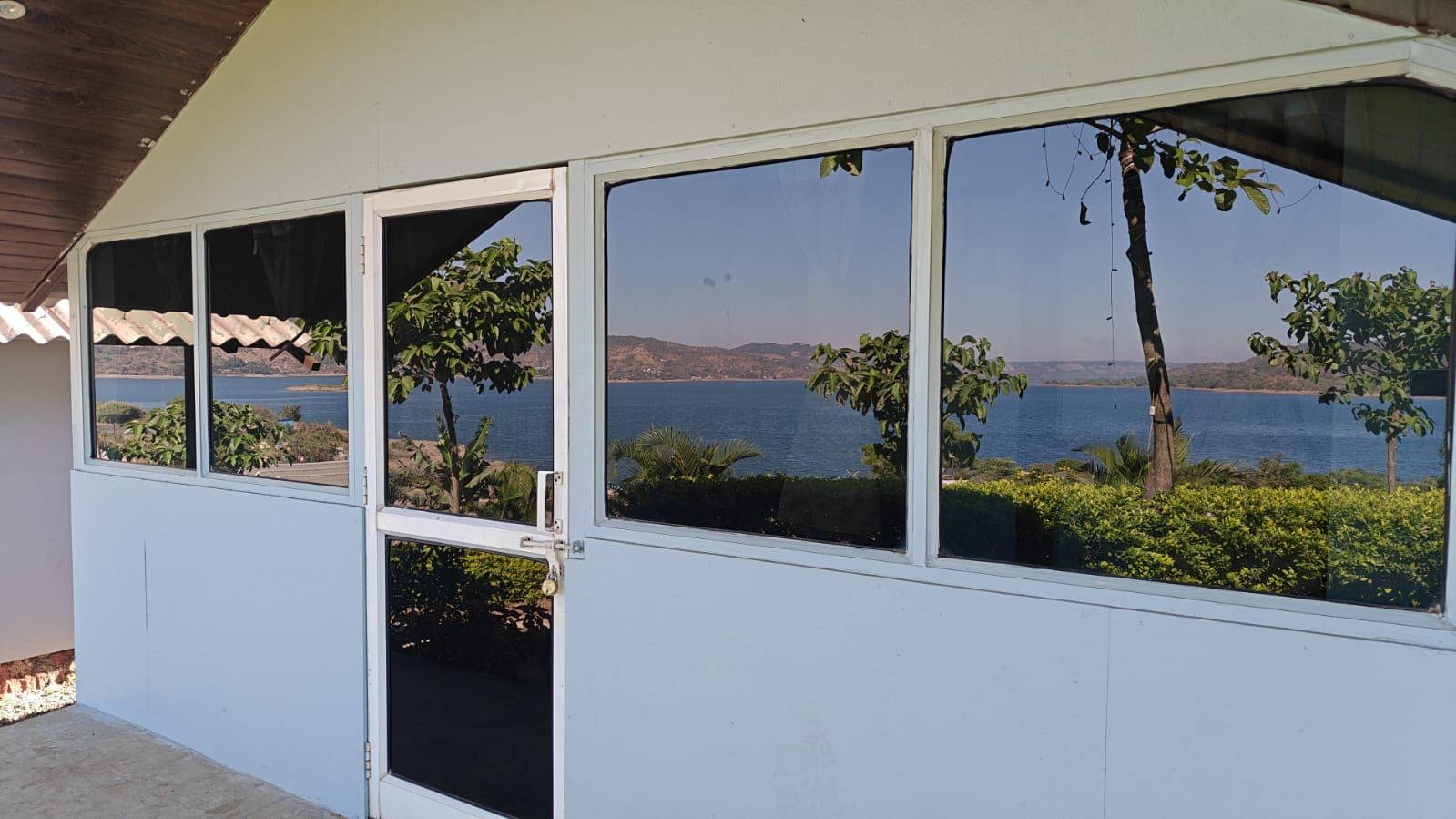 A covered outdoor area with a view of a body of water and hills.