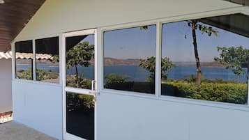 A covered outdoor area with a view of a body of water and hills.