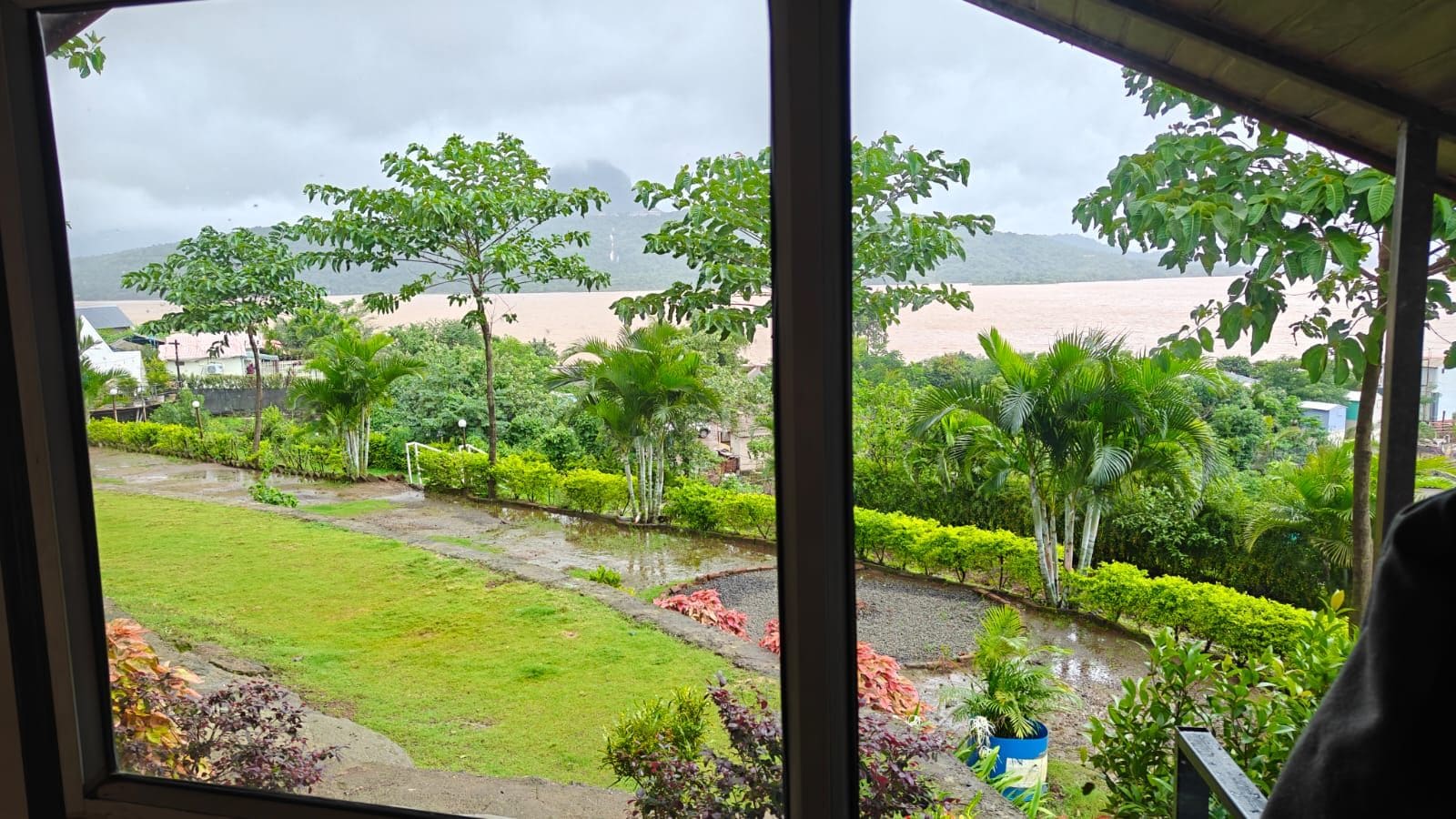 A view of a landscaped garden with a water feature and a distant body of water.