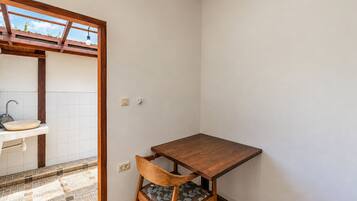 Une petite pièce avec une table en bois, une chaise, un évier et un sol carrelé.