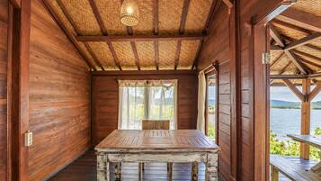 Une cabane en bois avec une table et un banc, un toit de chaume et une vue sur un lac.