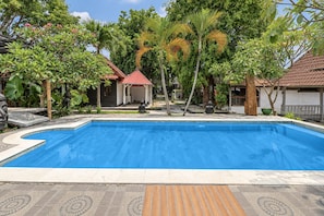 Piscina rectangular con borde de azulejos, rodeada por una zona pavimentada con baldosas podotáctiles para personas con discapacidad visual.