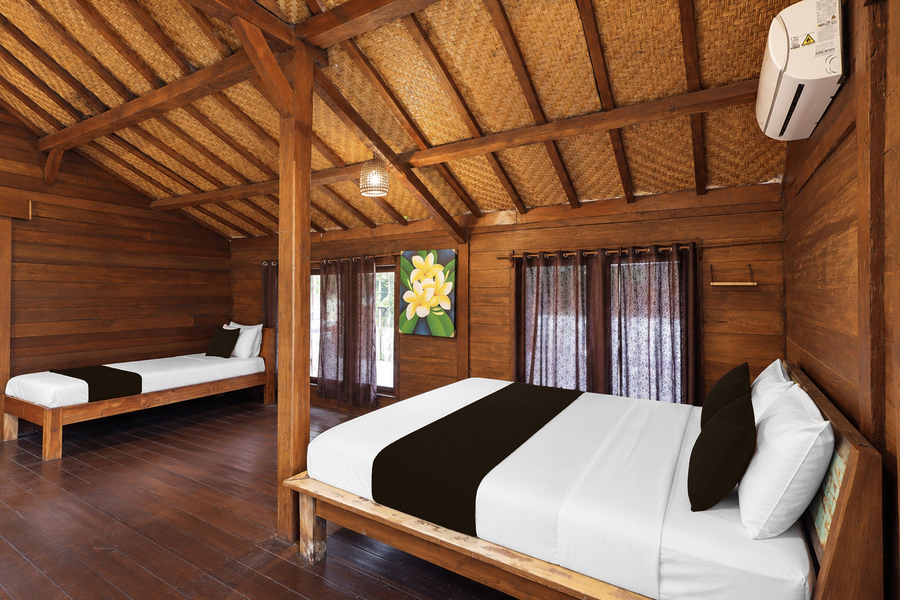 Een kamer met twee houten bedden, een plafondventilator en een bloemen schilderij.