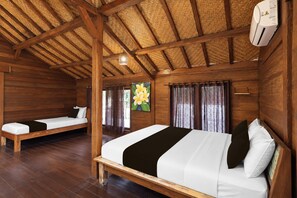 A room with two wooden beds, a ceiling fan, and a painting of flowers. - Collection O Surya Abadi Guest House  (Tibubeneng)
