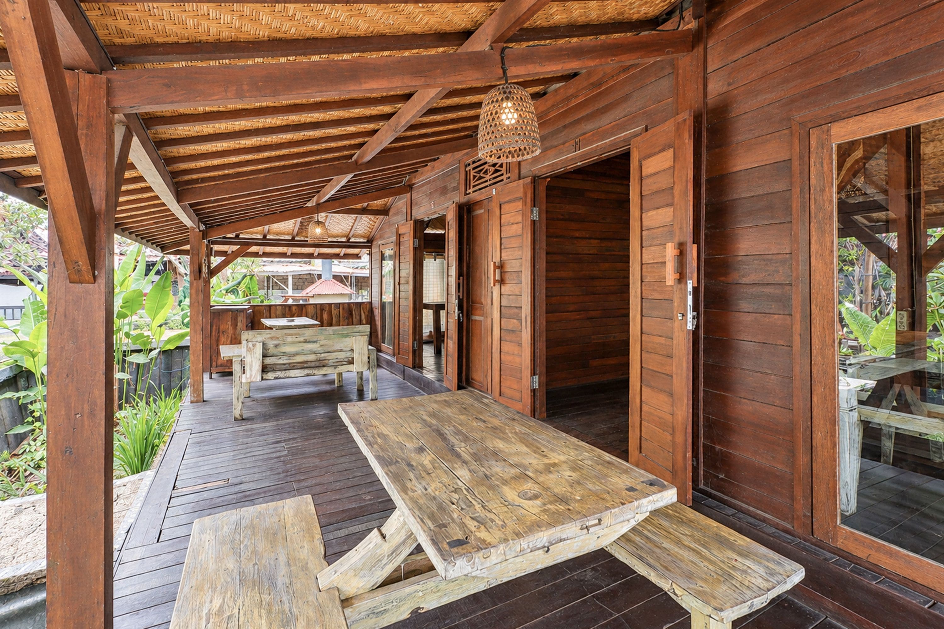 A wooden deck with picnic tables and a hanging light fixture.