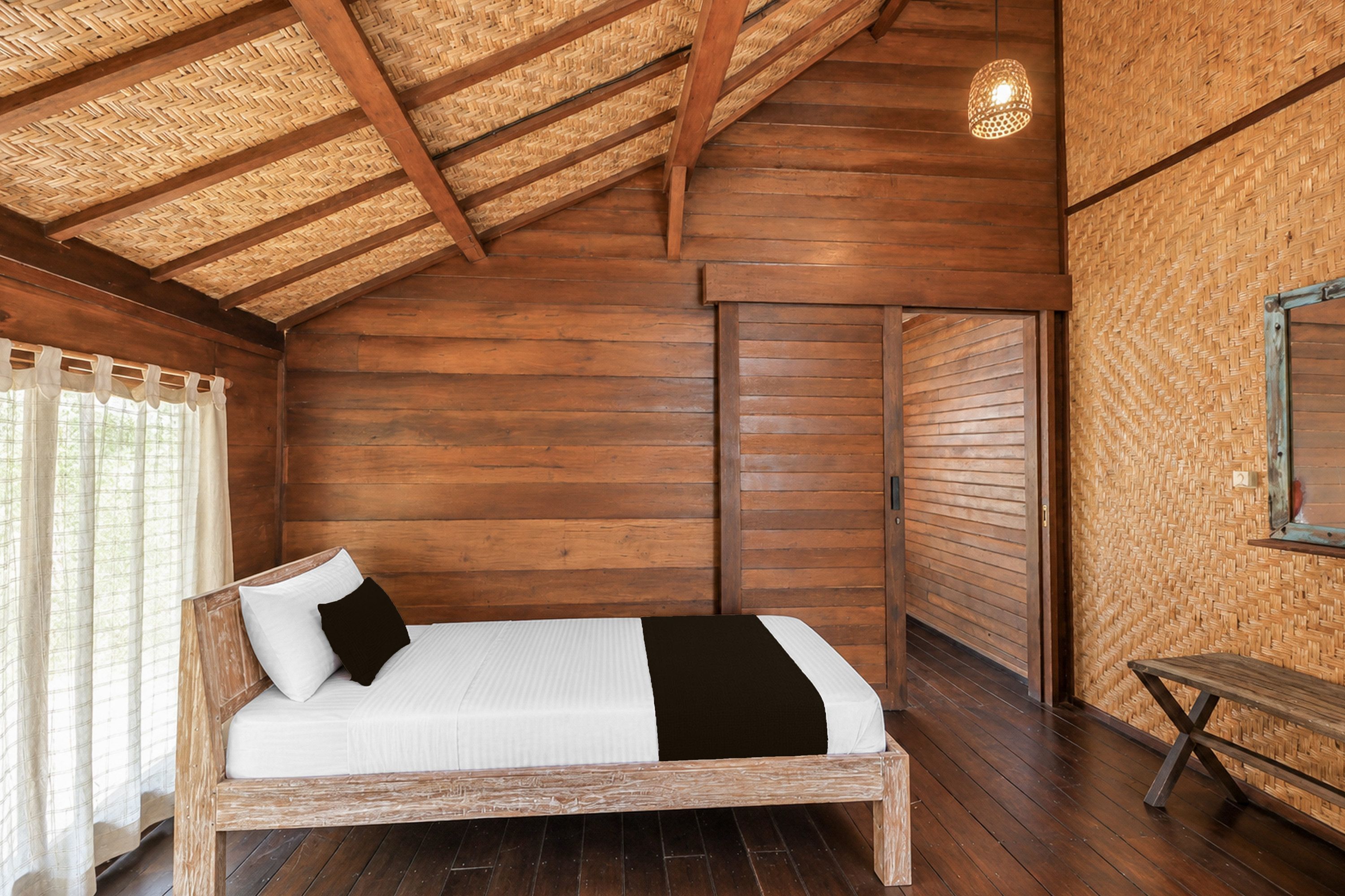 Une pièce en bois avec un lit, un banc et un plafond fait de fibres tressées.