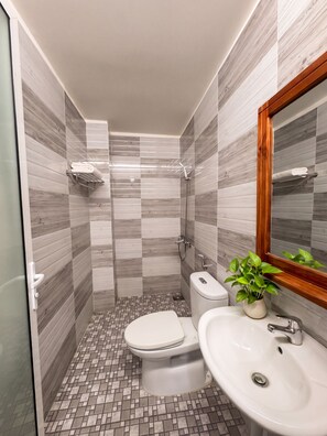 Een moderne badkamer met een douche, toilet en wastafel.