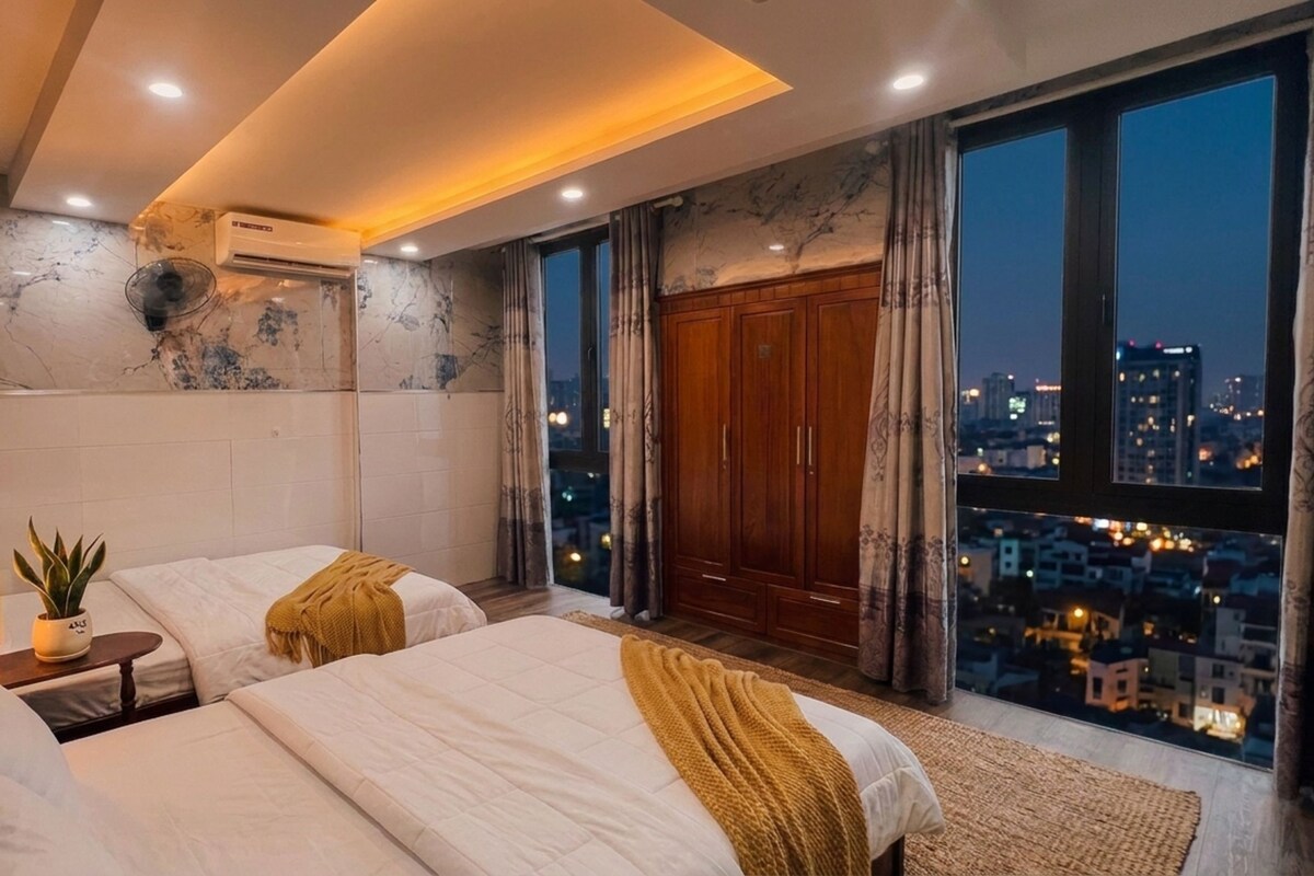 Een moderne slaapkamer met twee bedden, stadszicht en een ruime kledingkast.